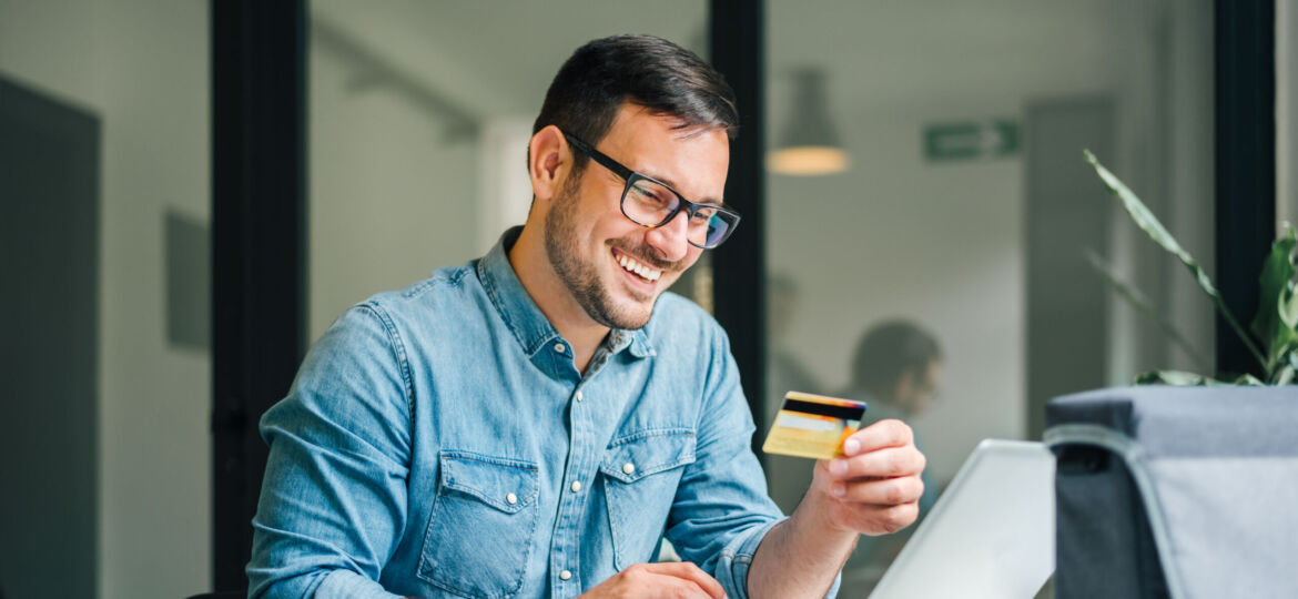 Happy cheerful smiling young adult man doing online shopping or