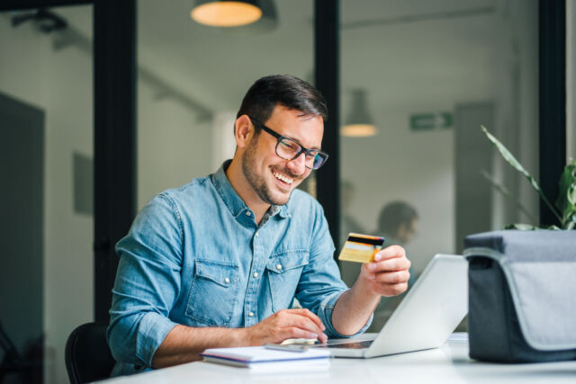 Happy cheerful smiling young adult man doing online shopping or