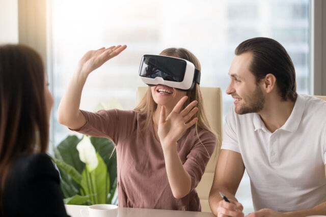 Woman wearing virtual reality headset, team developing VR glasse