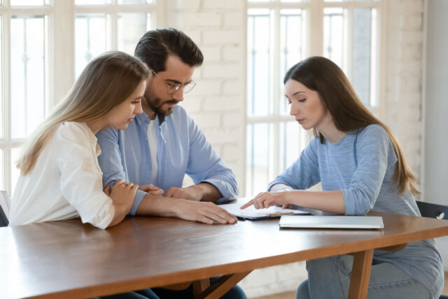 Young woman lawyer explaining agreement details to focused millennial spouses