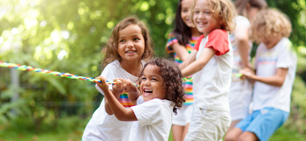 Kids play tug of war. Children pull rope.