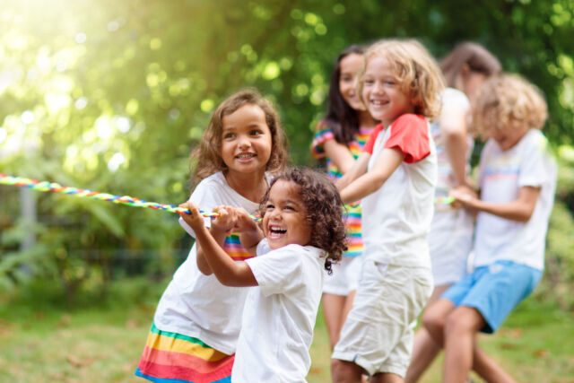 Kids play tug of war. Children pull rope.