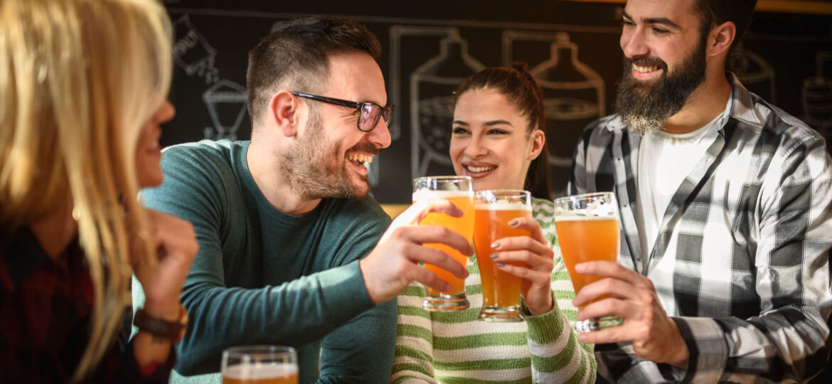 Smiling young people drinking craft beer in pub