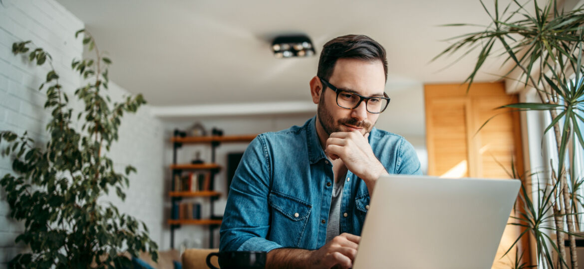 Portrait of a handsome man using laptop at home.