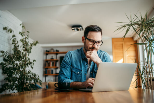 Portrait of a handsome man using laptop at home.