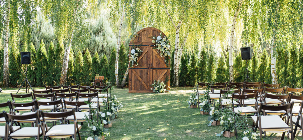 A beautiful area for an outdoor wedding ceremony. Arch Decorated with a large wooden door with many flowers.