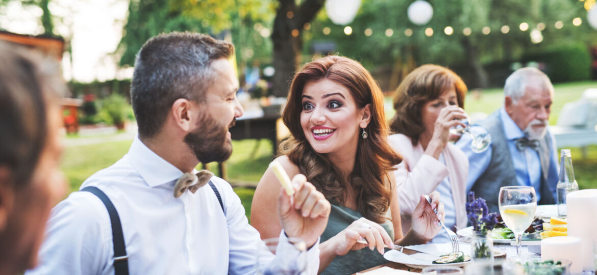 Guests eating at the wedding reception outside in the backyard.