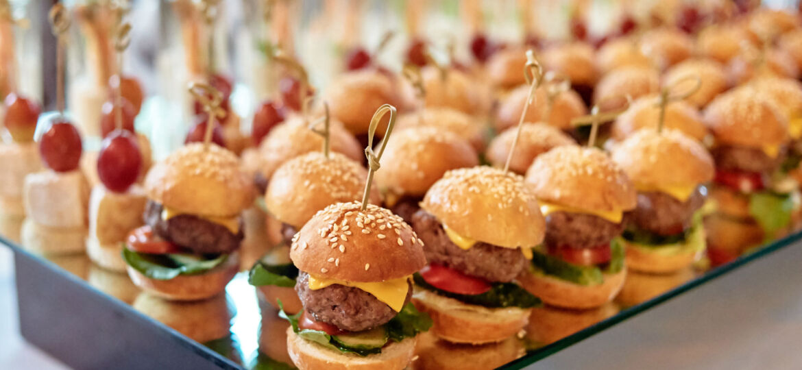 Buffet table with mini hamburgers and canape at luxury wedding reception, copy space. Serving food and appetizers at restaurant. Catering banquet table