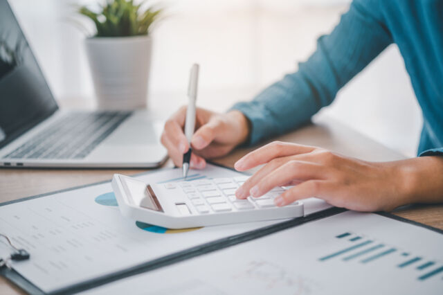 close up The business person is sitting on a calculator with a graph in the office of finance accounting concept