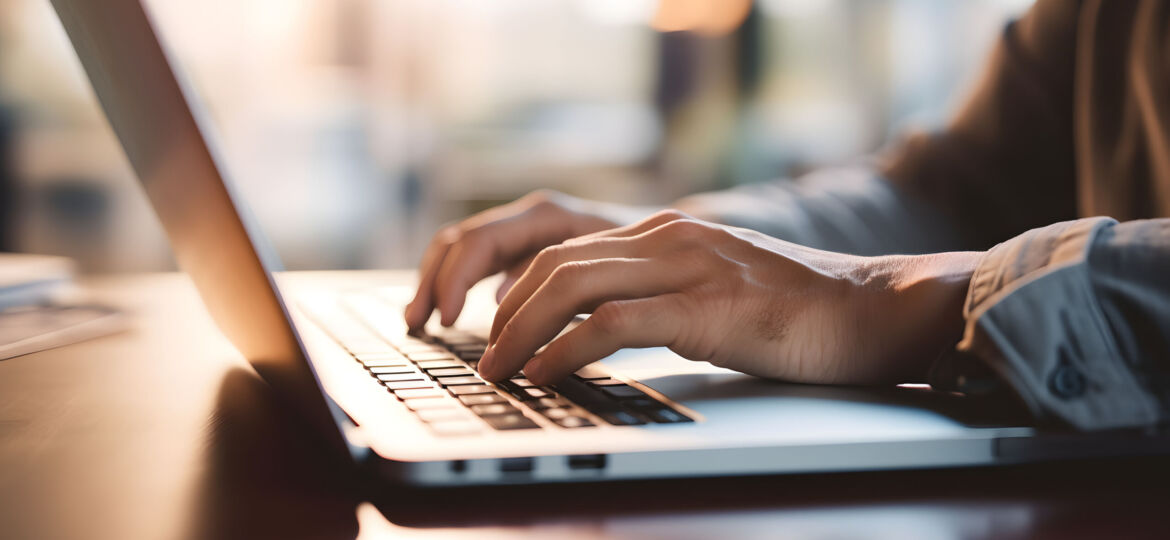 Close up of a business man working on a laptop, typing with his hands for work in office environment home office