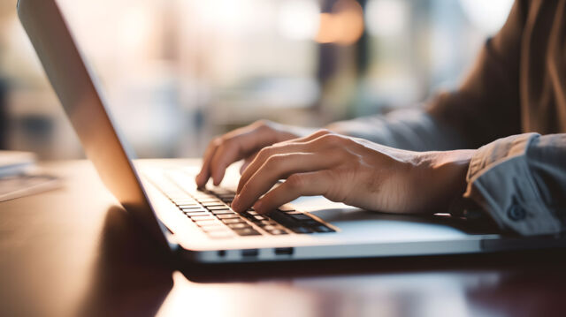 Close up of a business man working on a laptop, typing with his hands for work in office environment home office